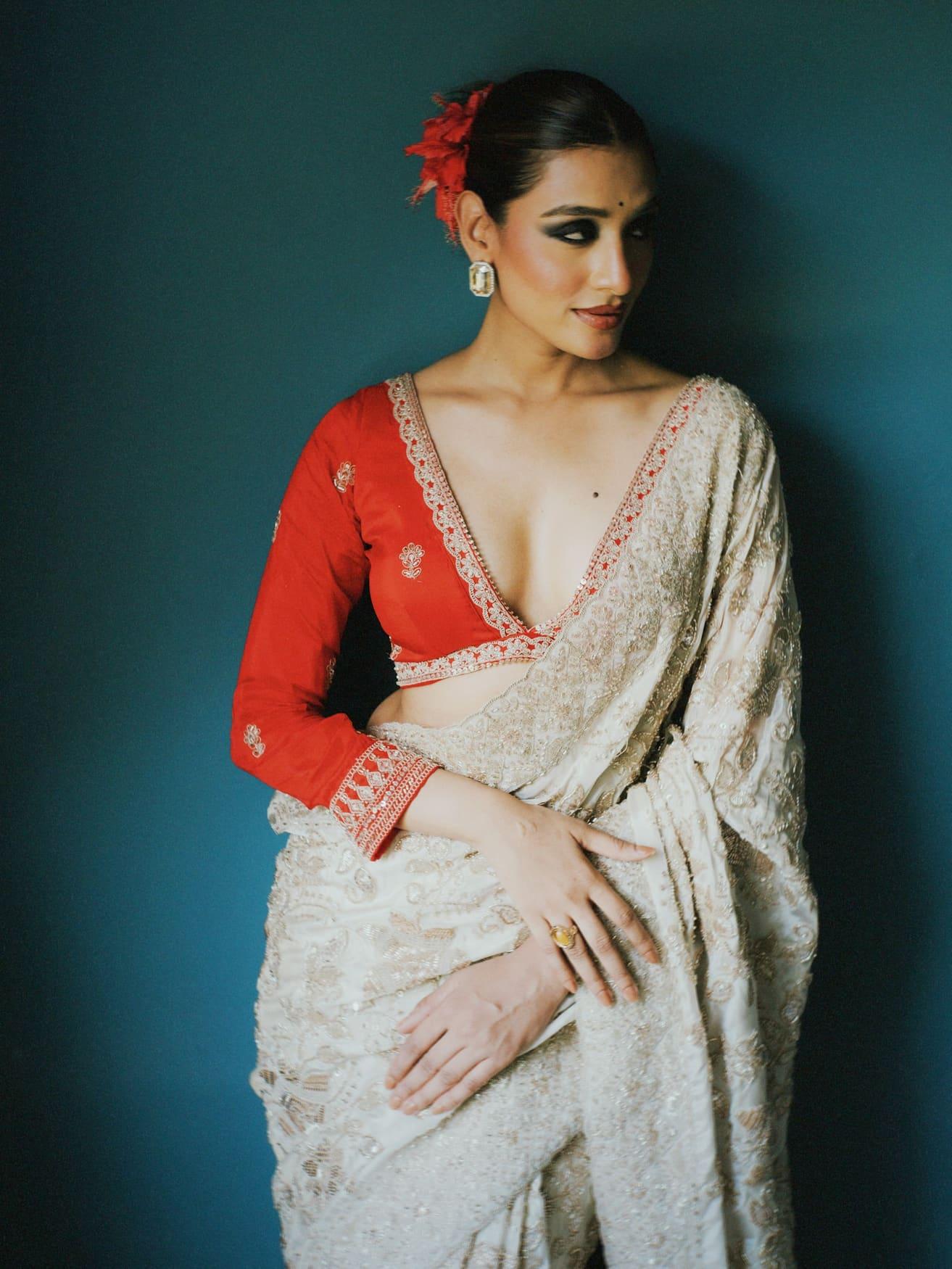 Red raw silk V-neck blouse with gold borders, worn with an ivory saree