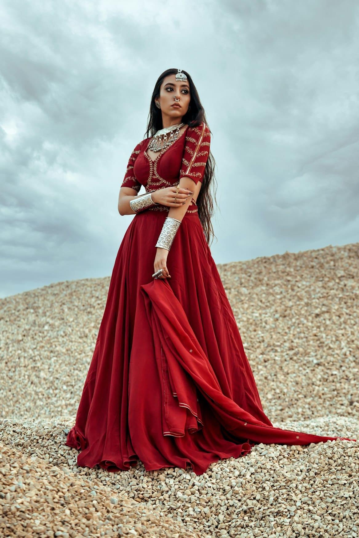 Woman in a flowing ruby red gown with gold jewellery